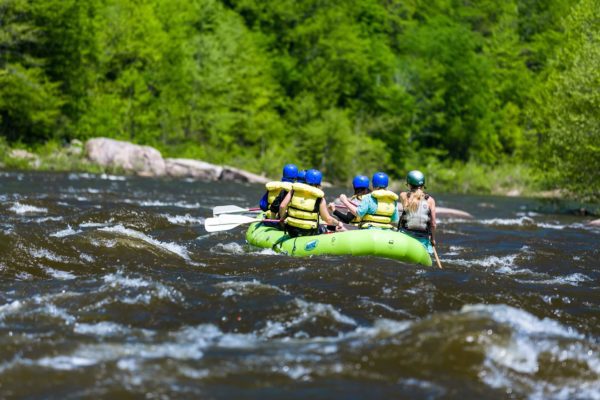 A whitewater raft with a family travels on a Canaan Valley river during a WV summer getaway.